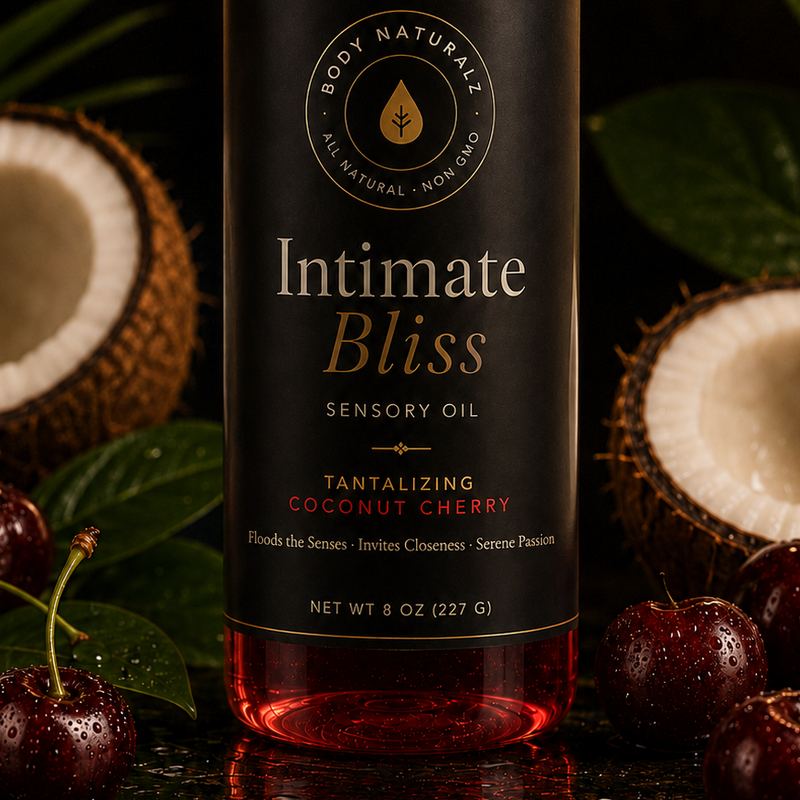 Intimate Bliss intimacy oil, an 8 oz bottle with a black and gold label and the Body Naturalz seal, beside halved coconut and fresh cherries.